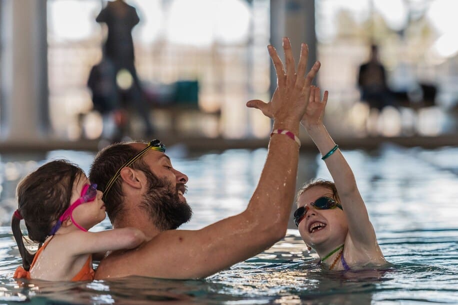 Dad high-fiving toddler in the pool